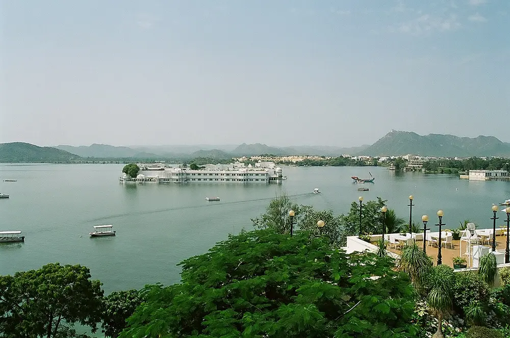 A wide lake with a white palace on an island in the middle, and hills behind.