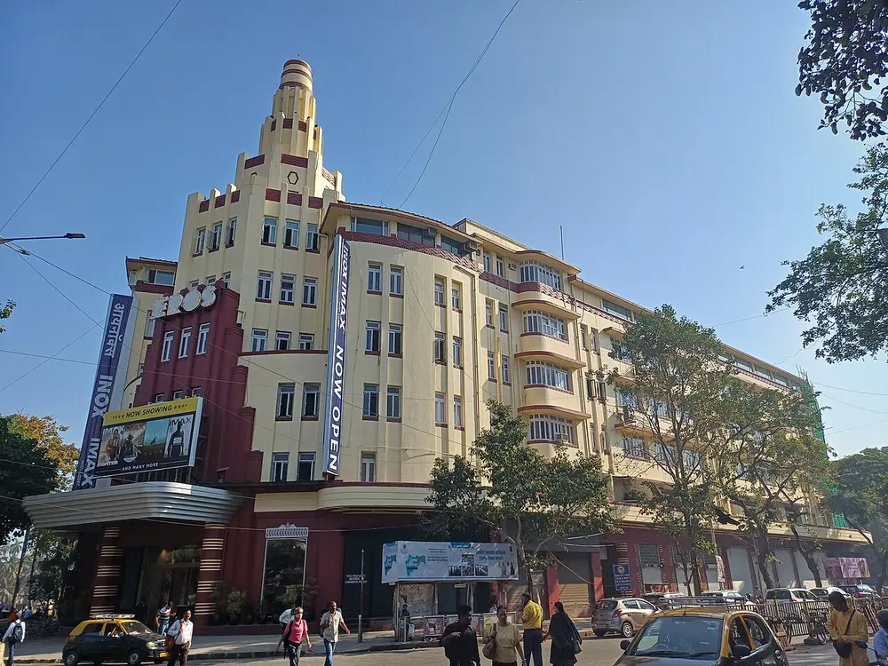The Eros Cinema building, a cream and red Art Deco block with rounded corners, a stepped tower over the corner entrance and a tall vertical sign.