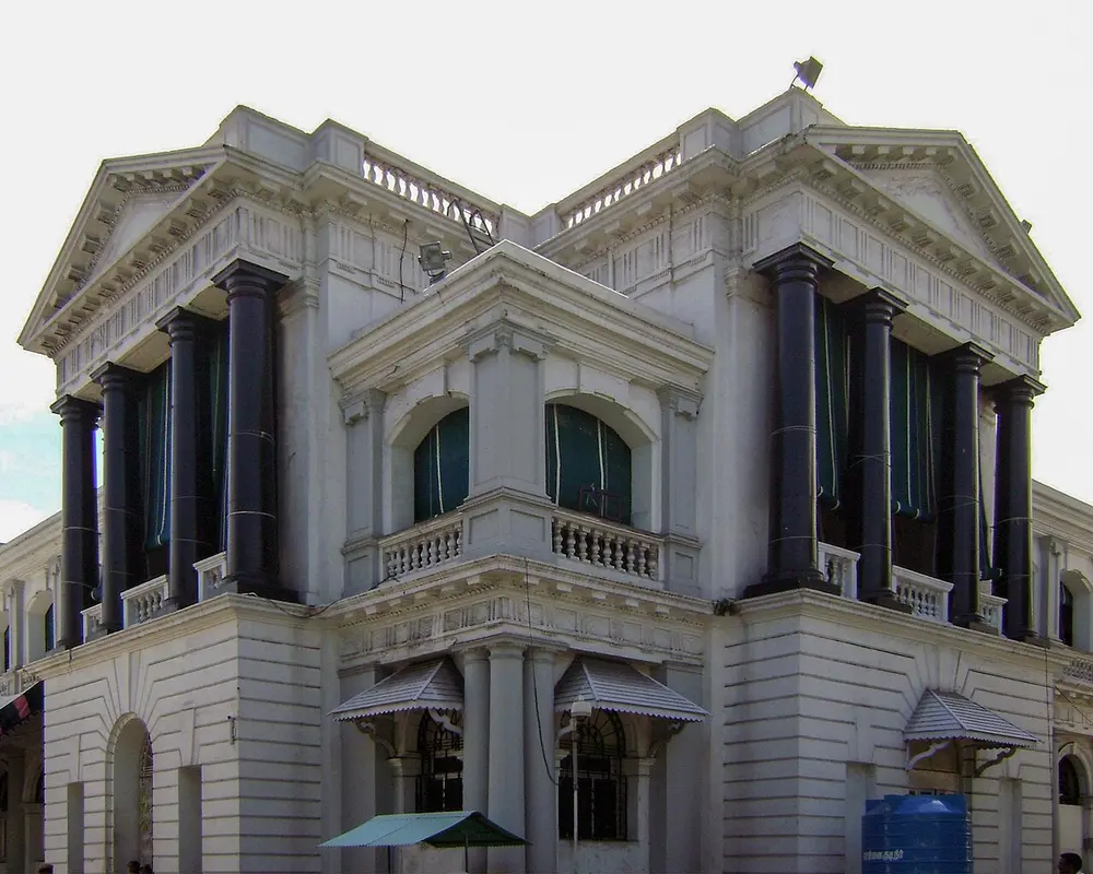 A white classical building inside Fort St George with tall, polished black stone columns, a balustraded balcony and a triangular pediment.