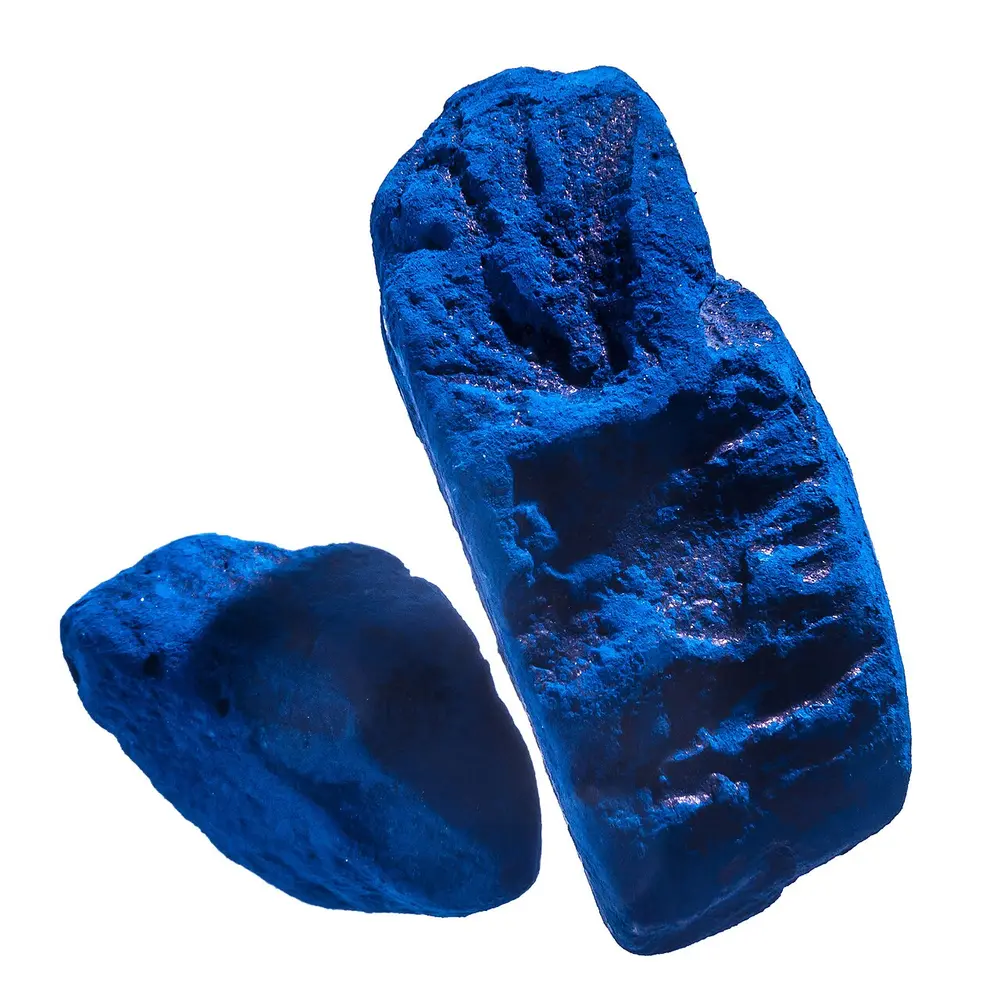 Two lumps of dried indigo dye, a deep bright blue, on a white background.