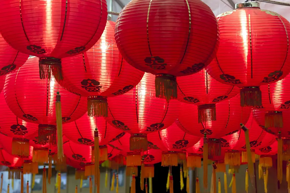 Rows of round red paper lanterns with golden tassels hanging close together.