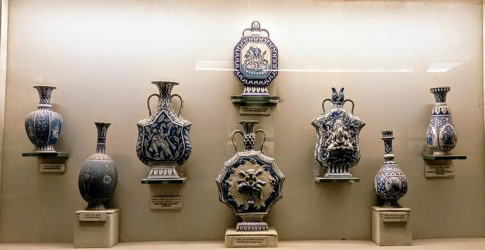 A museum wall case of blue and white glazed vases and flasks of different shapes, painted with flowers, figures and patterns.