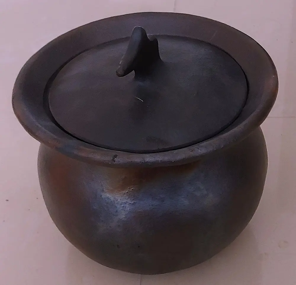 A round, dull black pot with a matching lid that has a small curved knob.