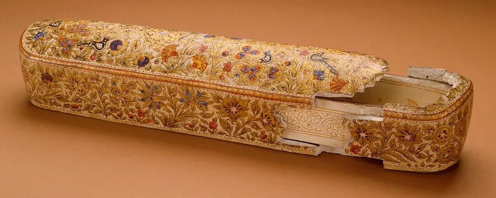 A long, narrow box with a sliding inner tray, its cream surface painted all over with tiny flowers in red, blue and gold.
