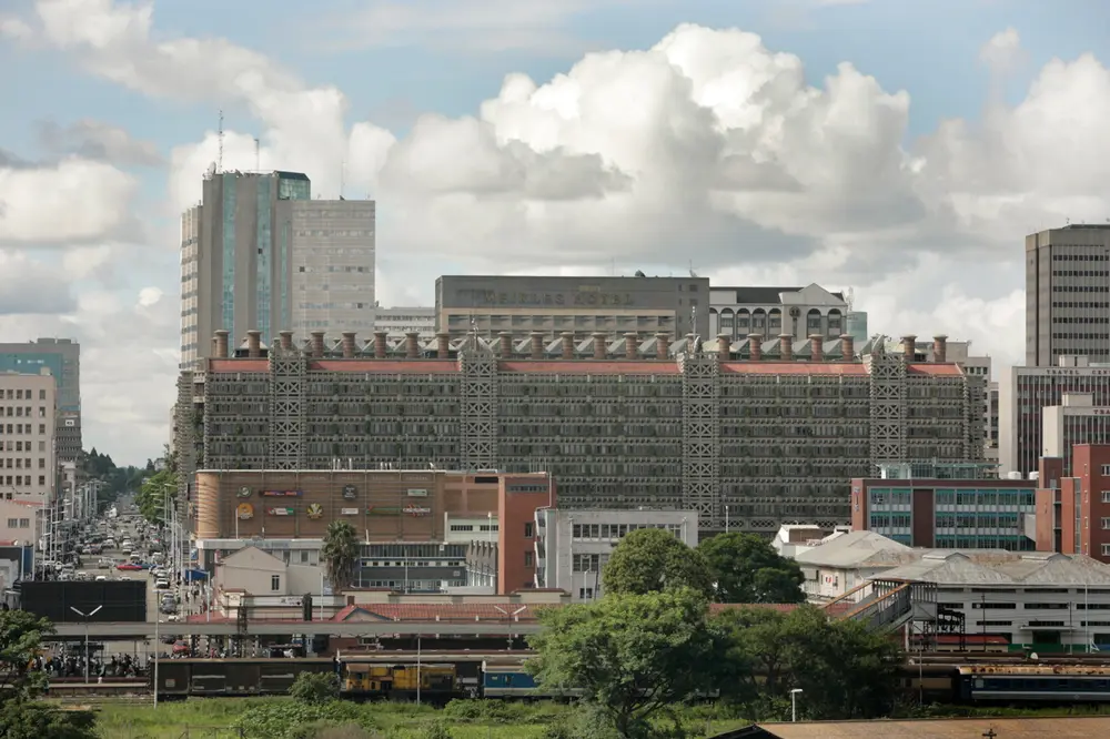 A view across a city centre to a long, low-rise block whose roof is lined with rows of tall brick chimneys.