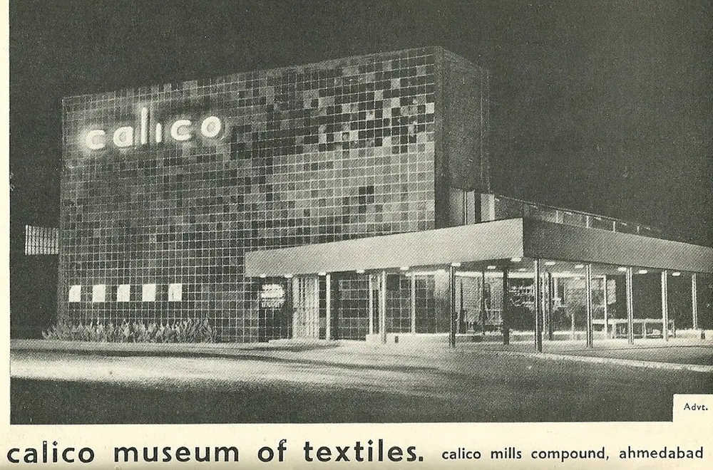 A 1952 black and white photograph of the original Calico Museum building, a block covered in square tiles with the word calico lit up, and a flat-roofed glass porch.