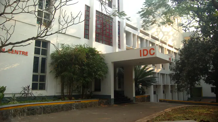 The white IDC building at IIT Bombay, with large red letters IDC on the porch above the entrance, behind trees.