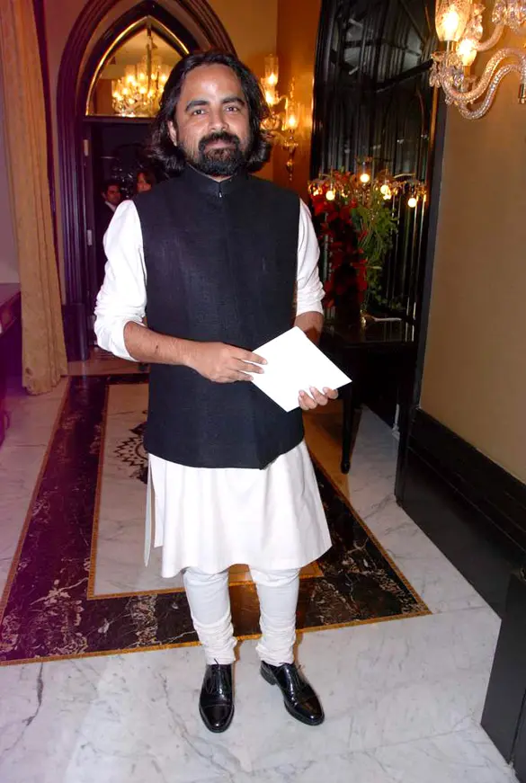 The designer Sabyasachi Mukherjee standing in a hotel lobby in a white kurta and a black sleeveless jacket.