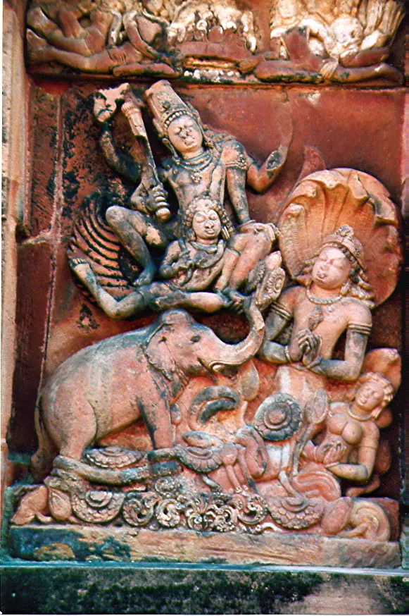 A red sandstone panel in a temple wall showing Vishnu riding on Garuda, a bird-man, swooping down to an elephant whose foot is caught by a snake king, who bows to Vishnu with folded hands.