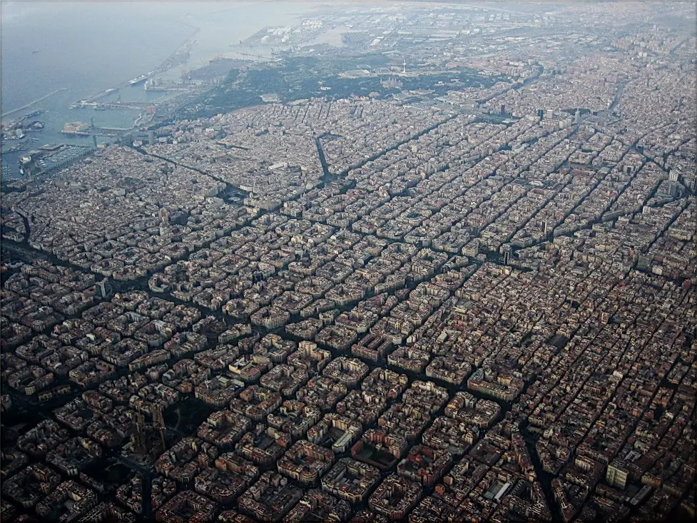An aerial view of a huge city laid out in a perfectly regular grid of square blocks, stretching to the sea.