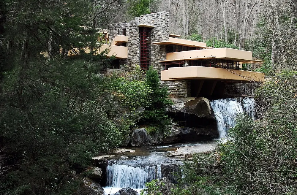 Fallingwater, a house of cream concrete terraces and stone walls jutting out over a waterfall in a forest.