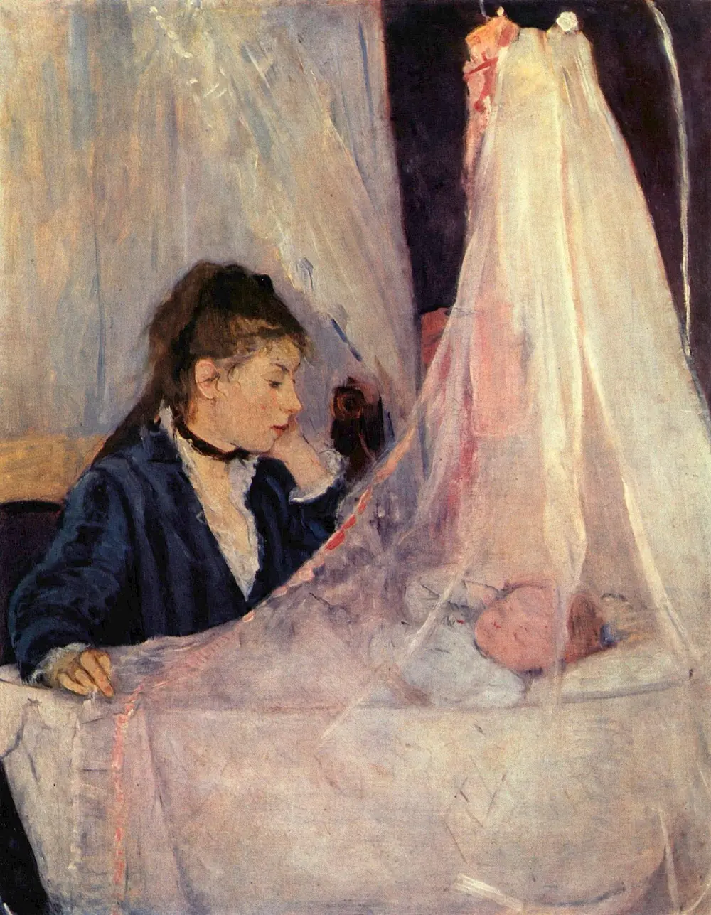 A young mother in a dark dress rests her chin on her hand and watches a baby sleeping in a cradle behind a soft, see-through pink-white curtain.
