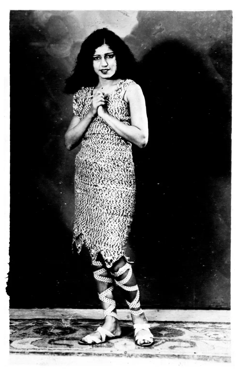 A black and white publicity photograph of the actress Zubeida as Alam Ara, standing barefoot in a sequinned costume with her hands folded.