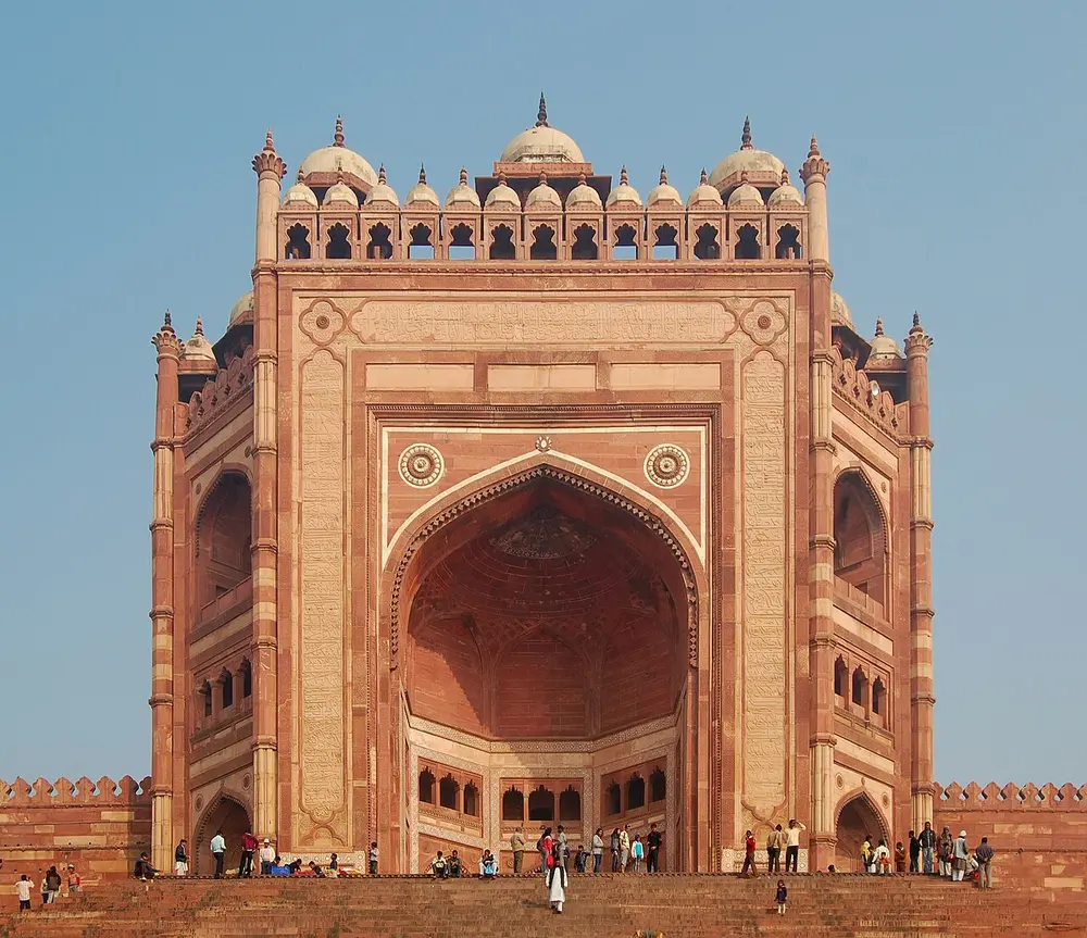 The Buland Darwaza, a huge red sandstone gateway with one giant arched recess in its face, topped by a row of small domed kiosks, above a wide flight of steps.