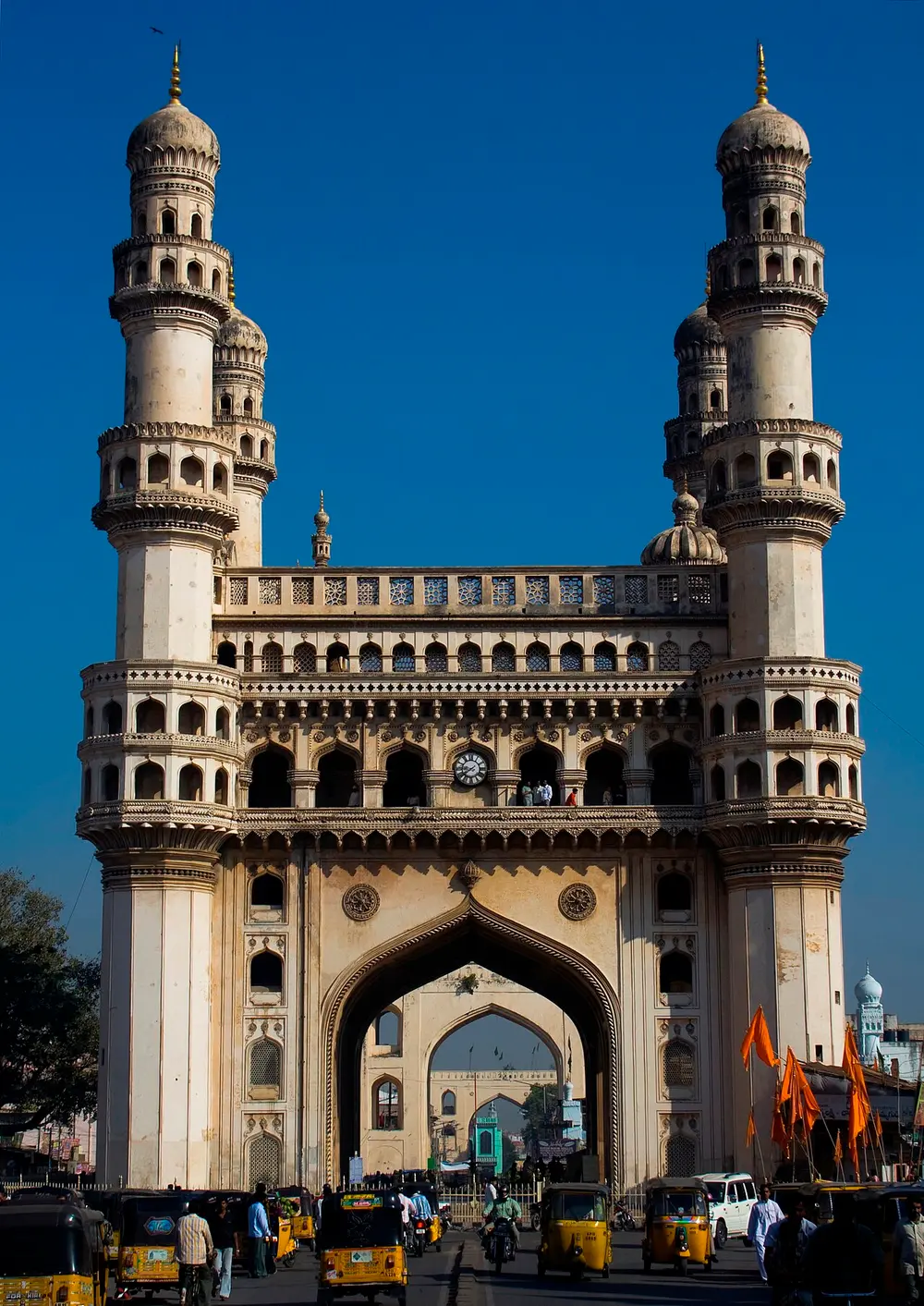 The Charminar, a square monument with a big pointed arch on each side and a tall, slim minaret at each of its four corners, rising above a busy street.