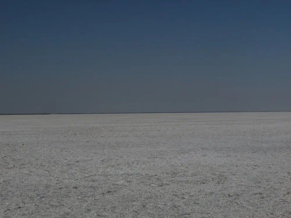 A flat white salt plain stretching to the horizon under a pale sky.