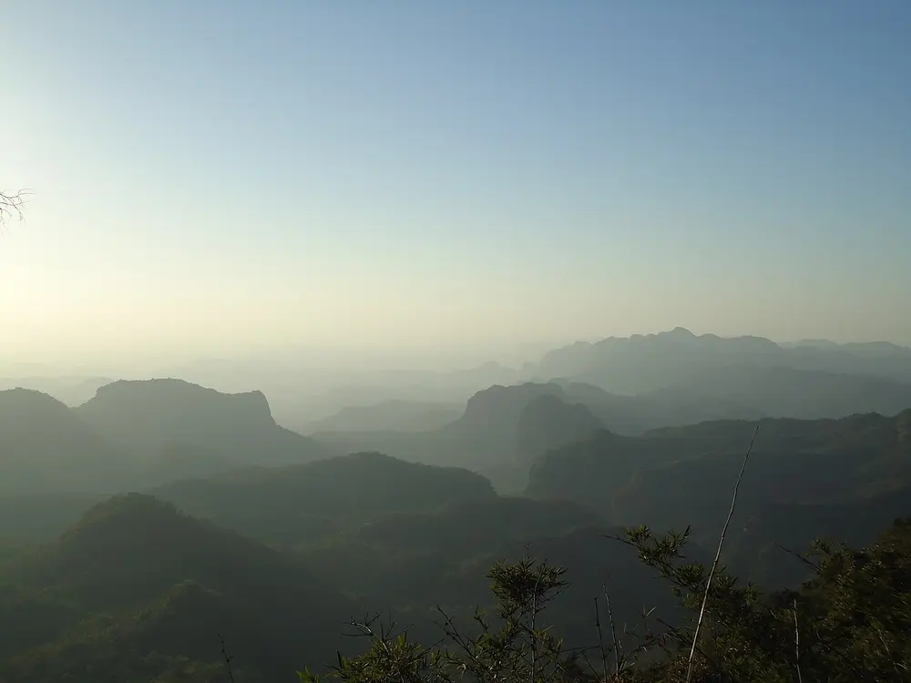 Flat-topped hills and deep valleys in morning haze, seen from above.