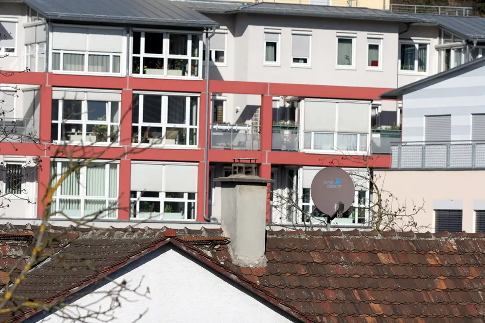 A close view of the same town: a few houses with balconies fill the frame, above a red-tiled roof and a chimney.