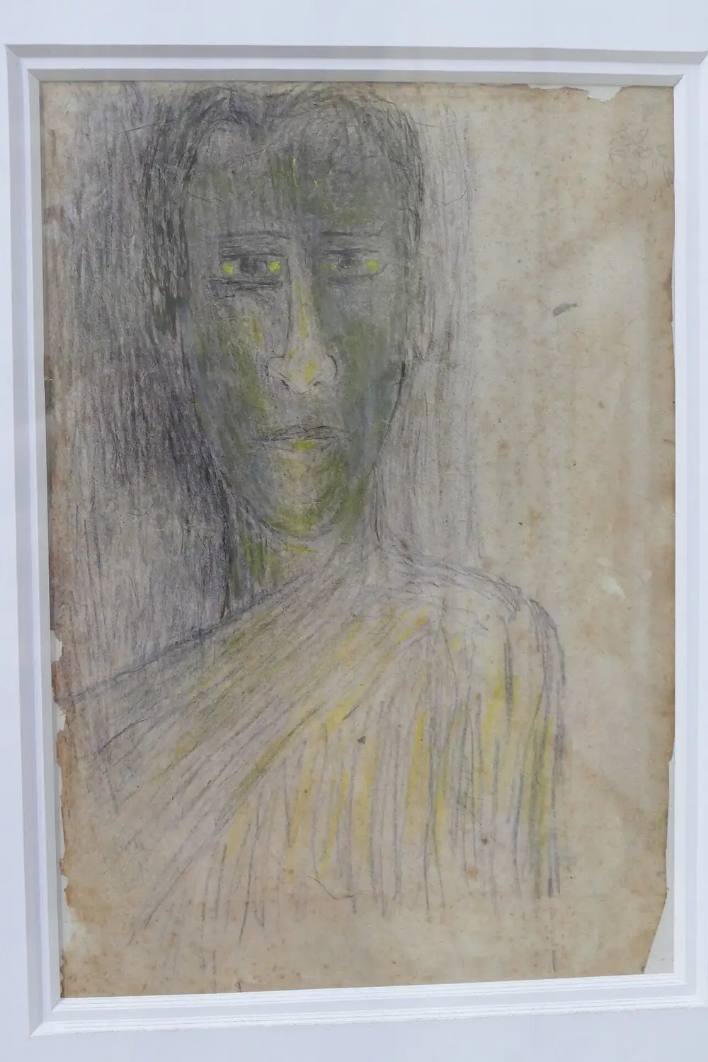 A scratchy drawing of a long-haired figure with a greenish face, yellow-tinged eyes and a shawl over the shoulders, made with loose grey and black strokes on stained, aged paper.
