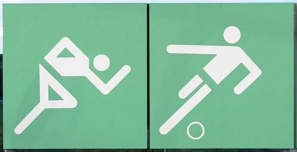 Two square green signs with white stick figures made of straight bars and circles: a runner leaning forward and a footballer kicking a ball.