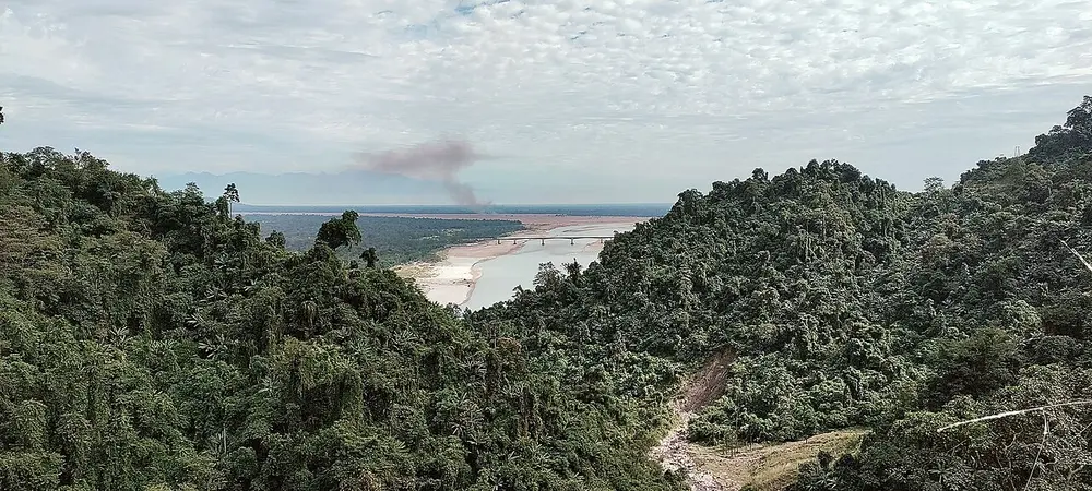 Forested hills in the foreground, with a wide river and its sandbanks opening onto a plain beyond.