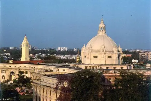 The large domed building of the state assembly seen above the rooftops and trees of a city.