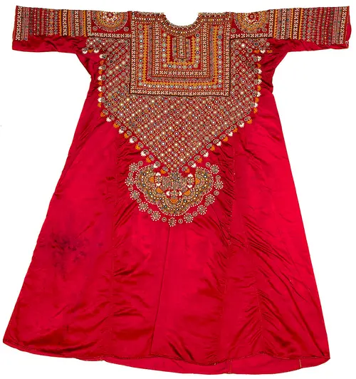 A red silk bride's shirt from Kutch, its chest and sleeves densely embroidered with tiny mirrors and coloured geometric patterns.