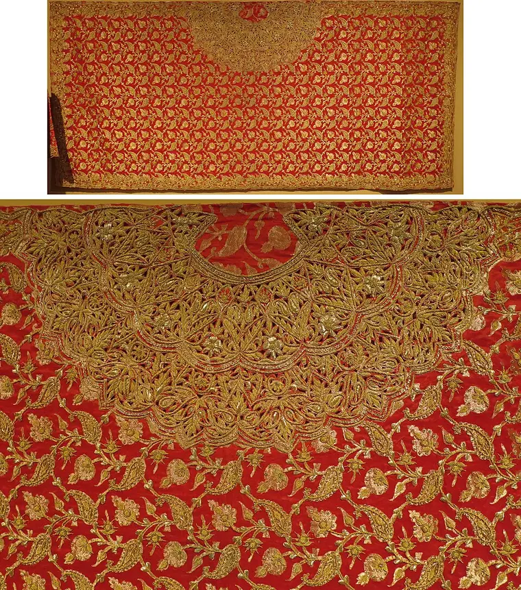 A red silk bridal garment in a museum covered with gold metal-thread flowers and leaves, with a dense golden yoke at the neck.