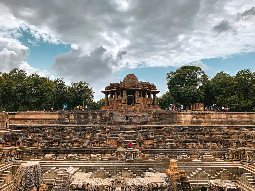 A large stepped stone water tank at Modhera, lined with tiny shrines, with a carved pillared hall at the top of the steps.