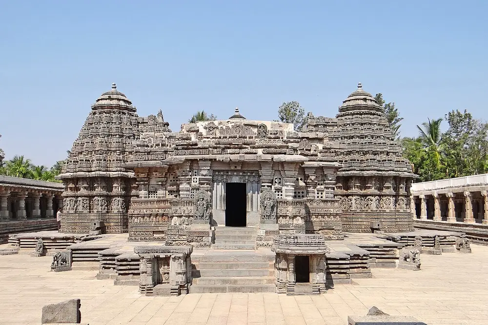The Keshava Temple at Somanathapura, a grey stone temple on a raised platform, with two of its three star-shaped towers visible on either side of the central doorway.