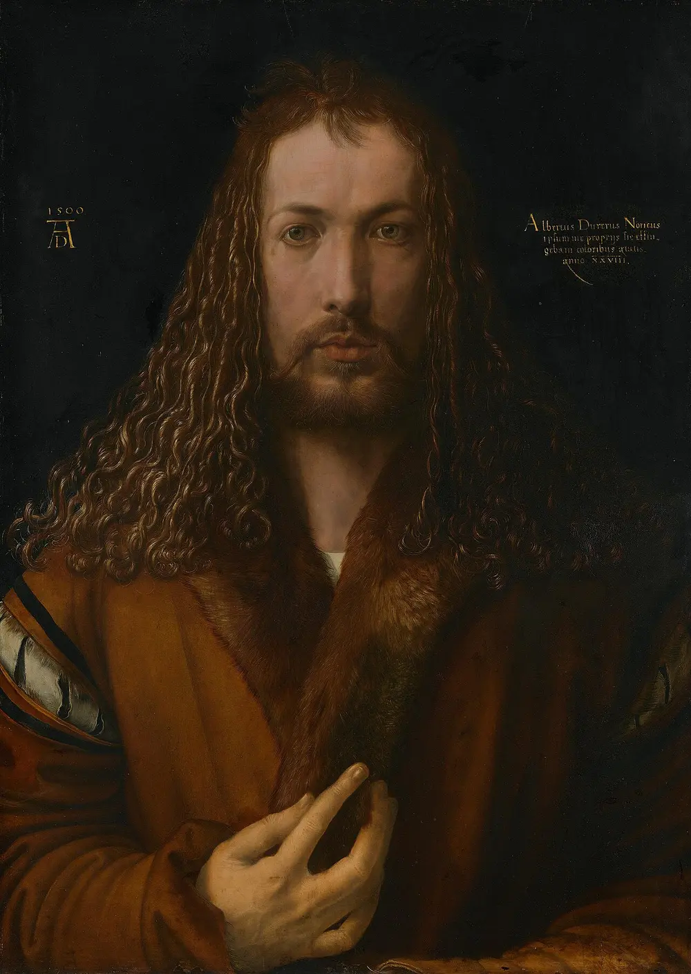 A front-facing portrait of a young man with long curling hair and a beard, wearing a fur-collared coat, one hand raised to his chest, against a dark background with the date 1500.