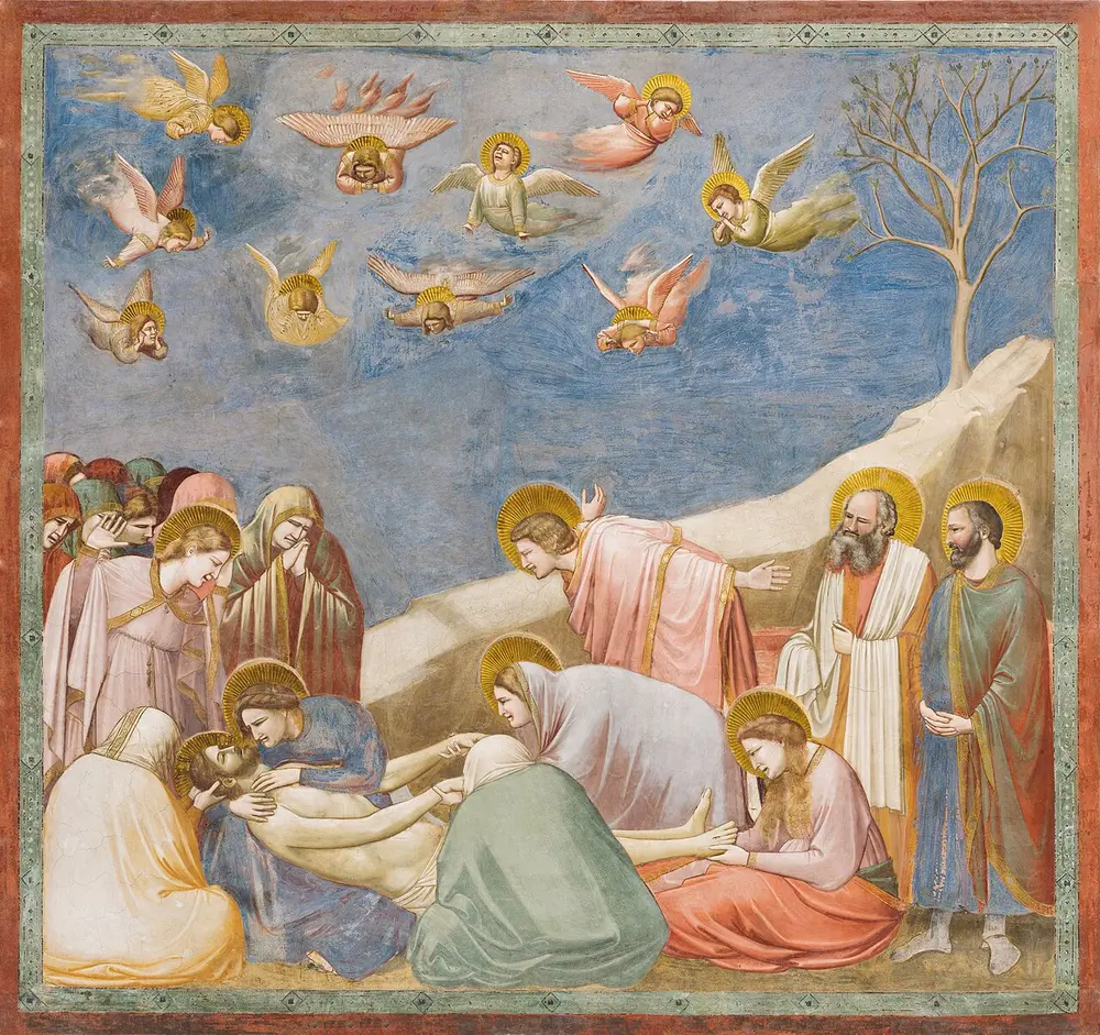 A fresco of mourners gathered around the body of Christ on the ground, with weeping angels flying in a blue sky and a bare tree on a rocky slope.