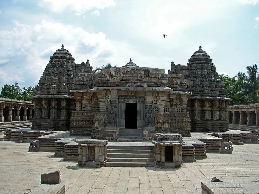 A low, richly carved stone temple with three short towers on a raised stone platform.