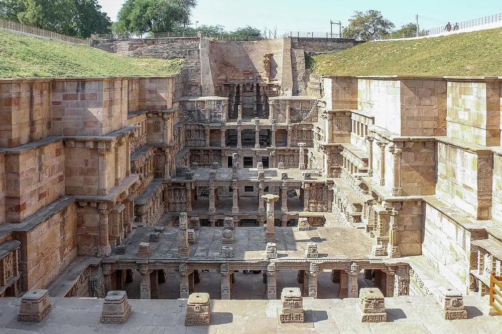 A deep stone stepwell with many levels of pillared galleries going down into the ground.